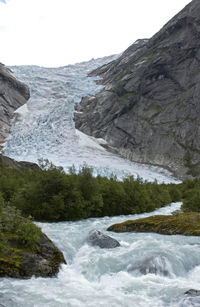 Scenic view of stream flowing through rocks against sky