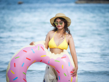 Portrait of woman with inflatable ring standing against sea