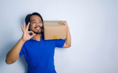 Portrait of smiling young man holding mobile phone while standing against wall