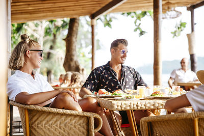 Smiling heterosexual couple sitting at table with breakfast in resort