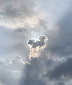 Low angle view of sunlight streaming through clouds