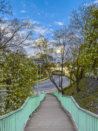Footbridge amidst trees against sky