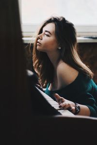 Young woman looking away while sitting on floor