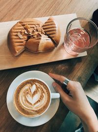 High angle view of hand holding coffee on table