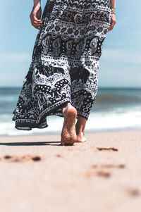 Low section of woman walking at beach