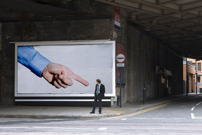 Full length of man walking on road by building