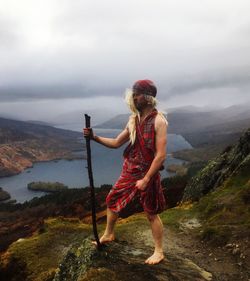 Man standing on mountain against sky during foggy weather