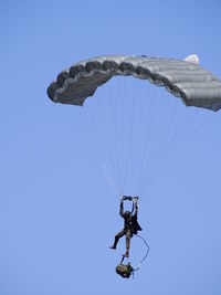 Low angle view of person paragliding against clear blue sky