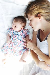 Close-up of mother with baby on bed at home