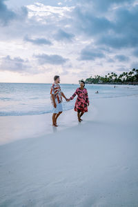 People walking on beach against sky