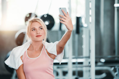 Portrait of young woman standing against wall