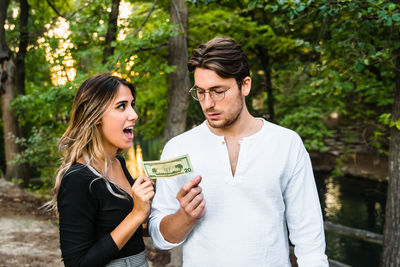 Young couple standing against trees and plants