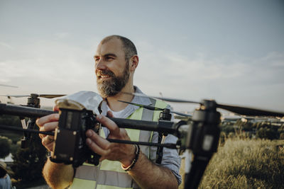 Man holding drone while standing against sky