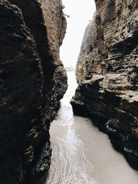 Rock formations by river against sky