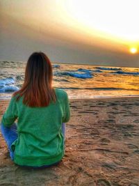 Rear view of woman looking at sea during sunset