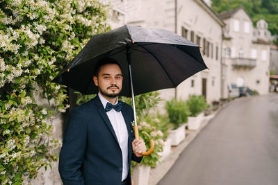 Portrait of woman with umbrella standing in city