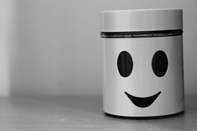 Close-up of smiley anthropomorphic face on mug against wall