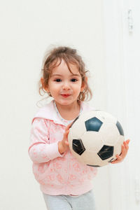 Portrait of smiling girl standing against wall