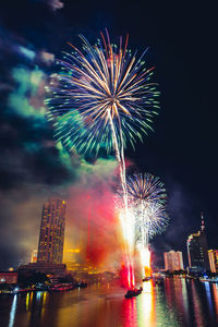 Firework display in city against sky at night