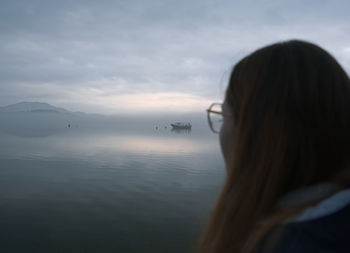 Rear view of woman standing at beach against sky