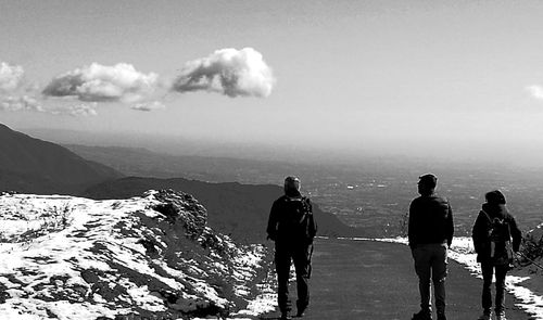 Rear view of people walking on mountain against sky