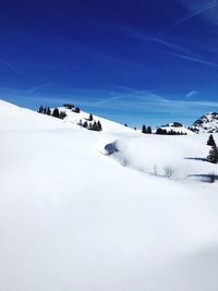 Snow covered landscape against blue sky