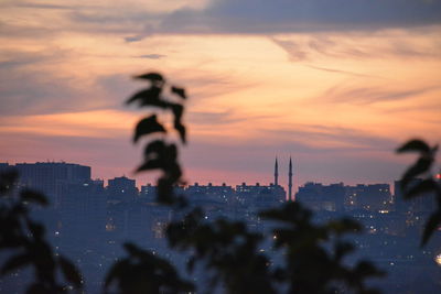 Silhouette buildings against cloudy sky during sunset