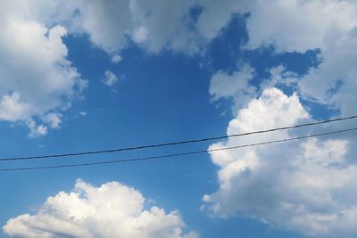 Low angle view of power cables against sky