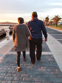 Rear view of couple walking on footpath