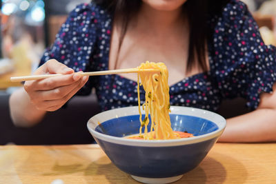 Midsection of woman holding ice cream in bowl on table