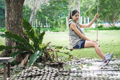 Woman sitting on swing at park