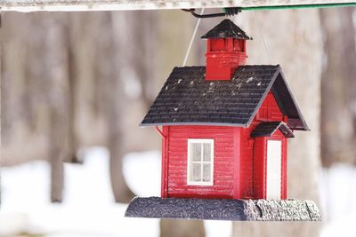 Close-up of red house hanging on roof during winter