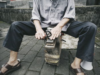 Low section of man sitting on seat in street