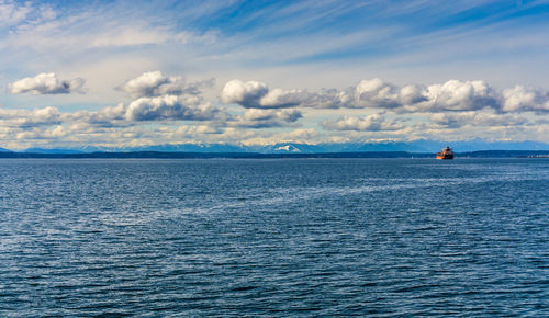 A tanker ship in elliott bay with the olympic mouintain range in the distance.