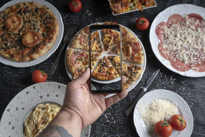 High angle view of hand holding pizza on table