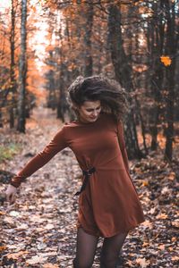 Smiling young woman standing in forest during autumn