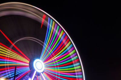 Low angle view of illuminated ferris wheel spinning at night