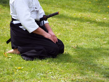 Low section of man with samurai sword on field