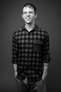 Portrait of young man standing against gray background