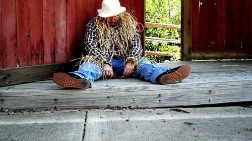 Man in scarecrow costume sitting in barn