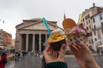 Two glasses of ice cream in the hands of a girl against roman pantheon in piazza della rotonda