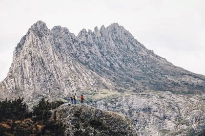 People on mountains against clear sky