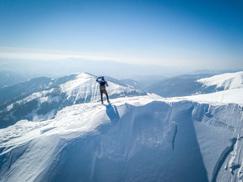 Man skiing on snowcapped mountain against sky