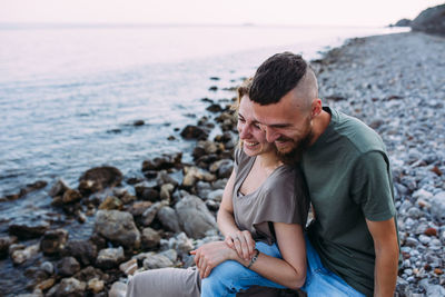 Stylish lovely couple walking and hugging by the sea enjoying time together