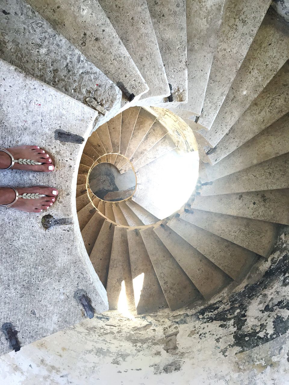 LOW SECTION OF PERSON WALKING ON SPIRAL STAIRCASE