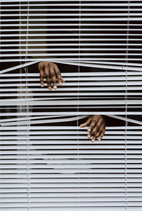 Man's hands out of window blinds