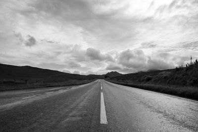 Empty country road against cloudy sky