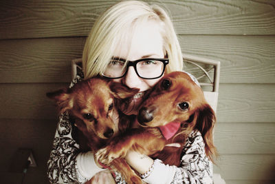 Portrait of smiling young woman embracing dachshund and chihuahua at home