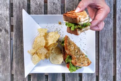 Close-up of hand holding sandwich over table