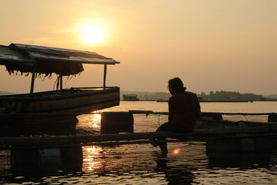 Man on boat in lake against sky during sunset